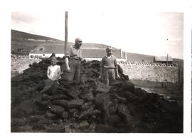 Man and children next to peat stack.